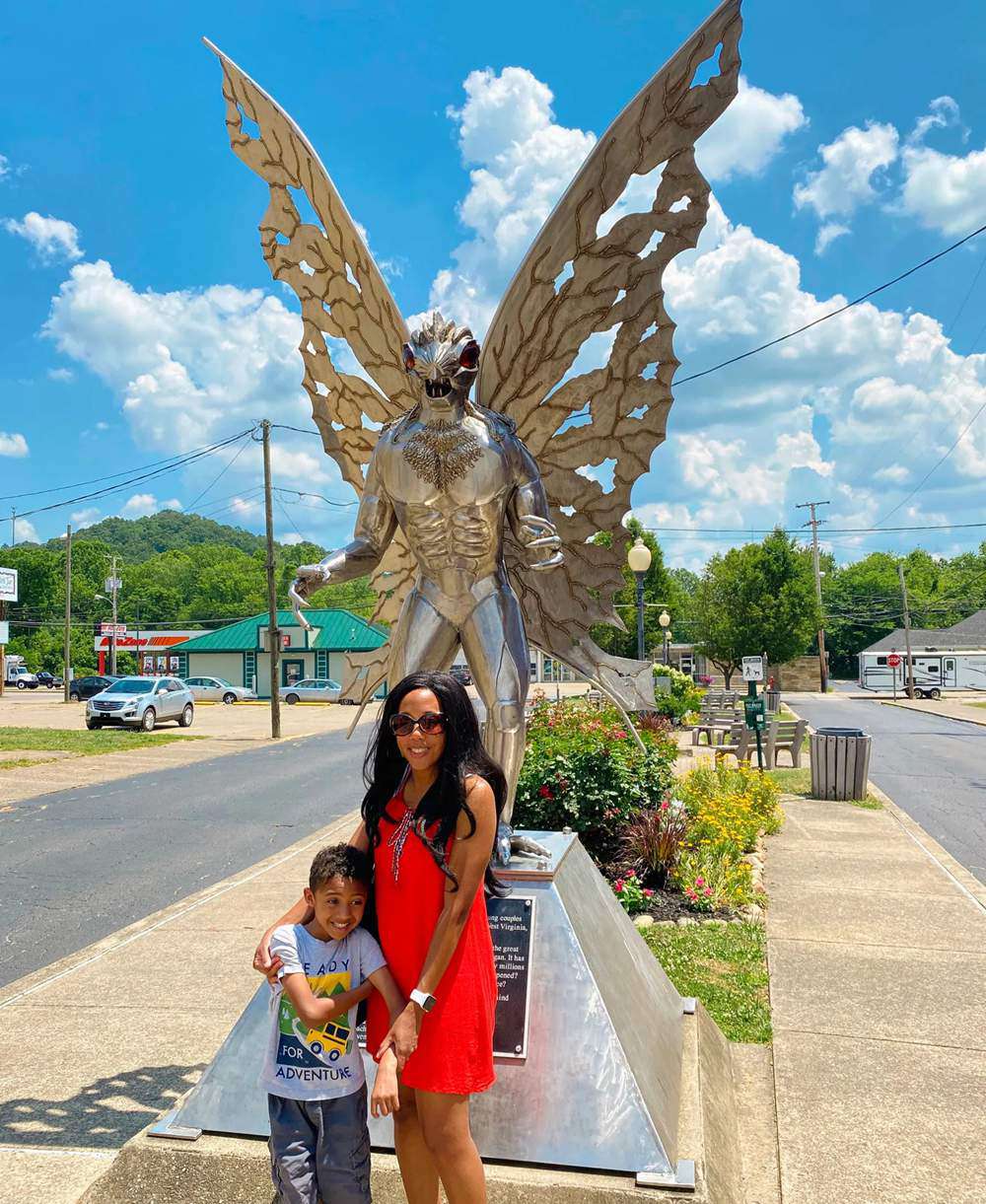 Tourists posing for a photo in front of the Mothman statue